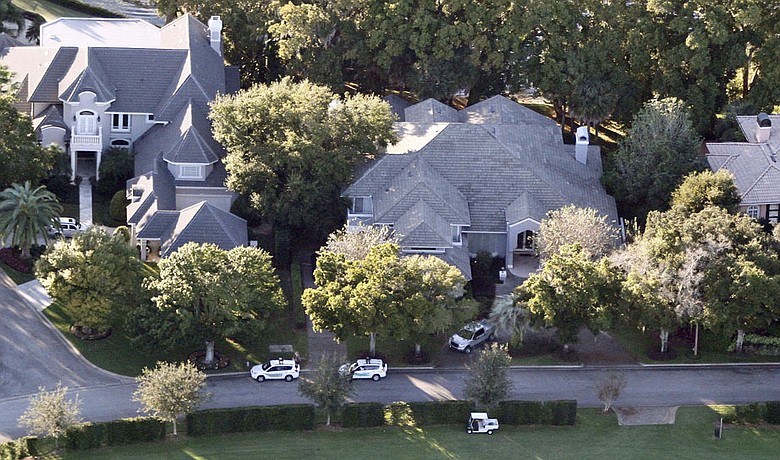 Security guards gather near the home, left, of Tiger Woods in Windermere, Fla.