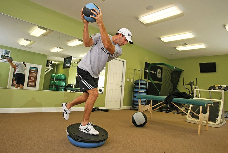 Dustin Johnson makes practice swings while standing on a balance disc.