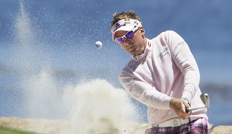 Ian Poulter blasts out of a bunker at the 18th.
