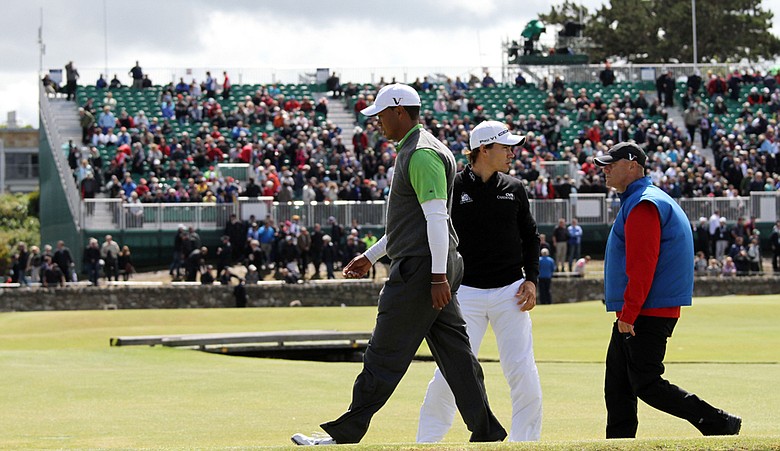 Tiger Woods walks back up the first fairway after play was suspended during Round 2 of the British Open.