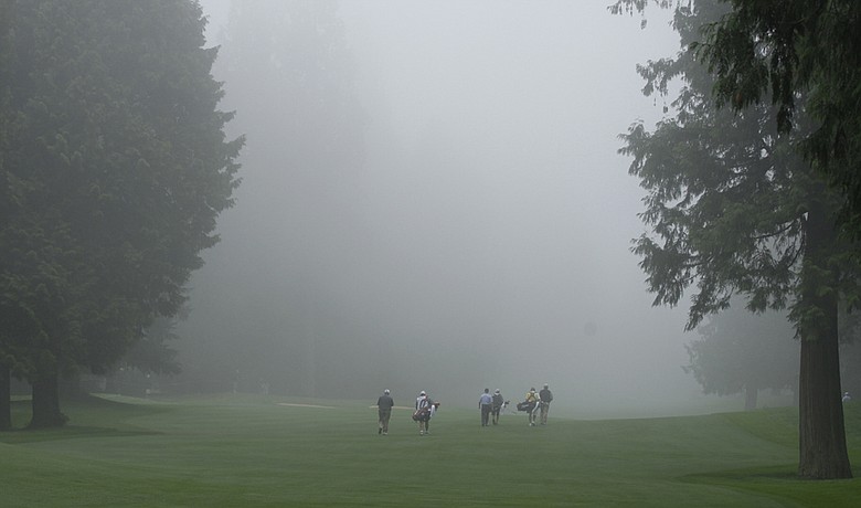Golfers, from left, Larry Stubblefield, Bill Britton, and Jon Fiedler, and their caddies, walk into the fog on the 1st fairway during the second round of the U.S. Senior Open.