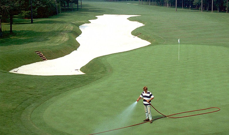 A greenskeeper cools down the greens prior to the 1990 PGA Championship at Shoal Creek.