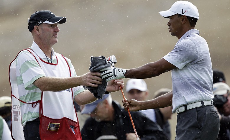 Tiger Woods, right, hands a club to his caddie, Joe LaCava, in the rain during the pro-am at the Frys.com Open Wednesday. This is LaCava's first tournament as Tiger's new caddie.