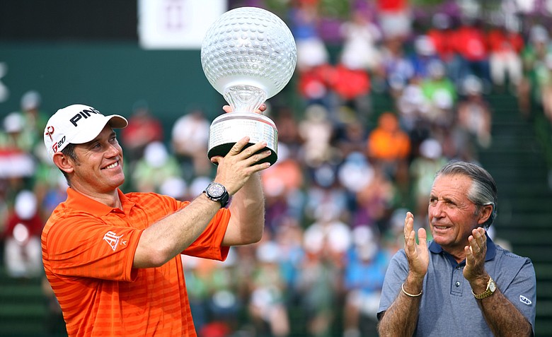 Lee Westwood of England holds the trophy aloft as tournament host Gary Player looks on after the final round of the Nedbank Golf Challenge.