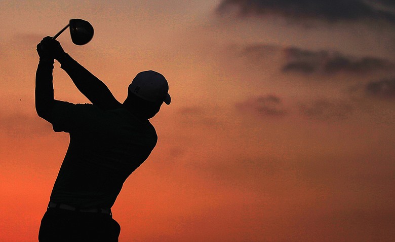 Tiger Woods on the driving range as the sun rises in the desert before teeing off in the first round.