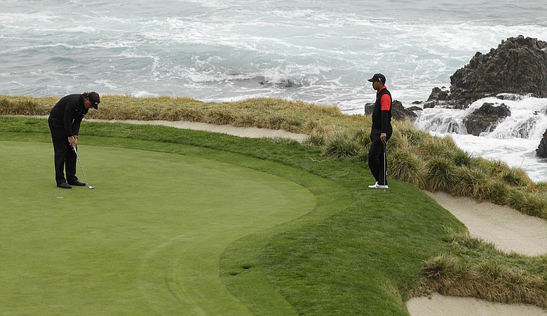 Tiger Woods, right, waits for Phil Mickelson to putt on the seventh green of the Pebble Beach golf links during the final round of the AT&T Pebble Beach National Pro-Am.