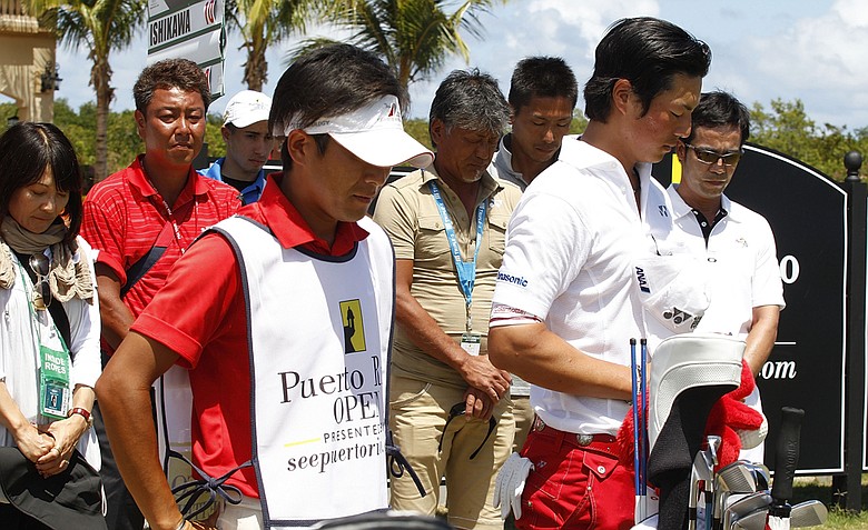Ryo Ishikawa, right, stands with his caddie Hiroyuki Kato and members of the media to observe a moment of silence on the first anniversary of the earthquake that devastated Japan during the final round of the Puerto Rico Open.