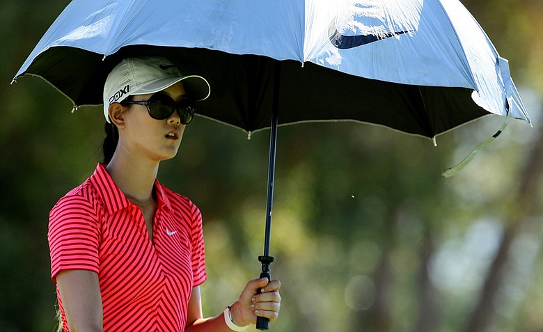 Michelle Wie uses an umbrella to shield herself from the sun on Friday at the Kraft Nabisco Championship.