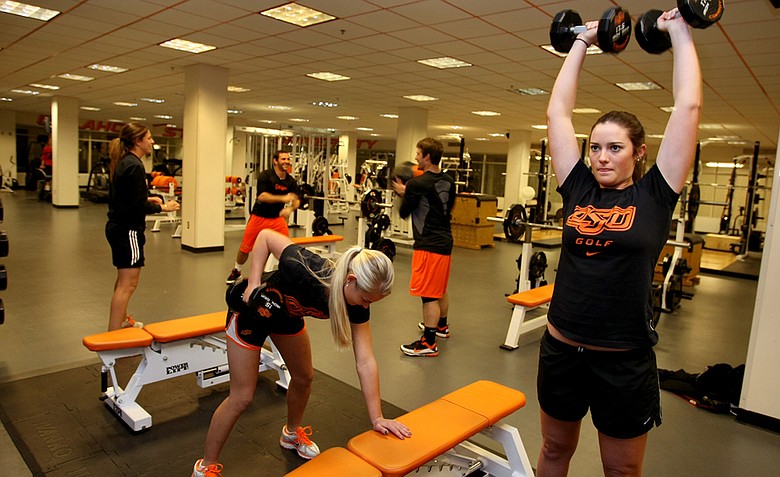 Oklahoma State players Kelsey Vines (right) and Josephine Janson work out while sharing the gym with members of OSU’s baseball team.