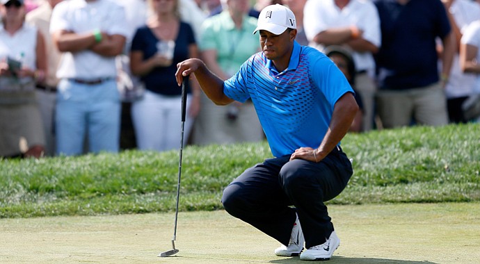 Tiger Woods gingerly bends down to line up a putt on the ninth green during the second round of The Barclays at the Black Course at Bethpage State Park August 24, 2012.