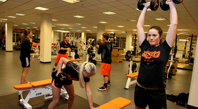 Oklahoma State players Kelsey Vines (right) and Josephine Janson work out while sharing the gym with members of OSU’s baseball team.