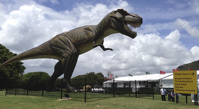 People stand near an 26-foot replica of a T-Rex standing between the 9th green and the 10th tee at the Sunshine Coast resort course in south Queensland, Australia, Tuesday, Dec. 11, 2012. The Australian PGA will move from its Sunshine Coast resort course location after 11 years, with blame lying indirectly, on the new robotic dinosaur.