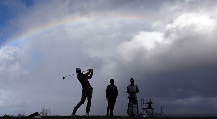 Dustin Johnson hits a tee shot under a partial rainbow on the 13th hole during the replay of the first round of the Hyundai Tournament of Champions at the Plantation Course.