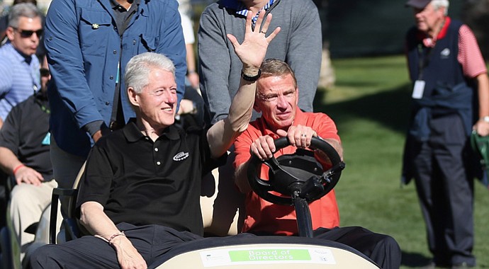Former President Bill Clinton waves to fans as he's driven around the course by PGA Tour Commissioner Tim Finchem during the first round of the Humana Challenge.