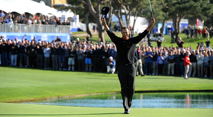 Tiger Woods celebrates on the 18th green after winning the Farmers Insurance Open.