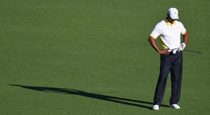 Tiger Woods reacts after hitting the flagstick and the ball bounding back off the green and into the water at the 15th hole on Friday.
