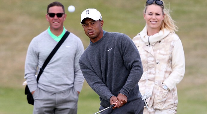 Tiger Woods plays a shot as his girlfriend, Lindsey Vonn, and his coach Sean Foley look on during a practice round for the 2013 Open Championship at Muirfield.
