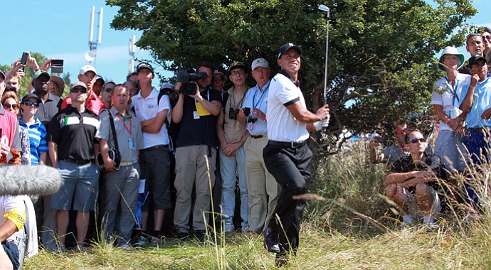 Tiger Woods had to take an unplayable lie after sending his tee ball into the long rough to the left of the first fairway. His third shot -- shown here -- found a right, greenside bunker. He got up-and-down to save bogey at the Open Championship.