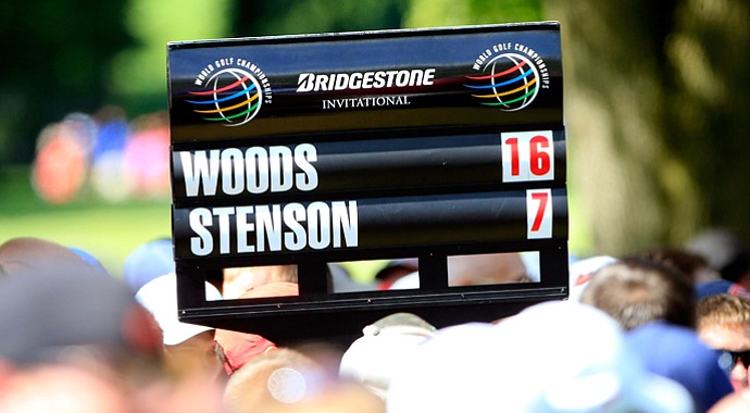 A standard bearer carries the scores of Tiger Woods and Henrik Stenson during the final round of the WGC-Bridgestone Invitational at Firestone Country Club.