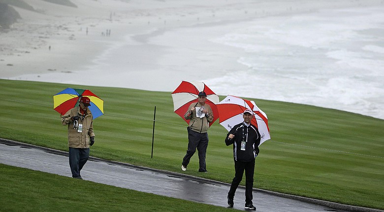 People walk in the rain along the ninth fairway of Pebble Beach Golf Links during the second round of the AT&T Pebble Beach Pro-Am.