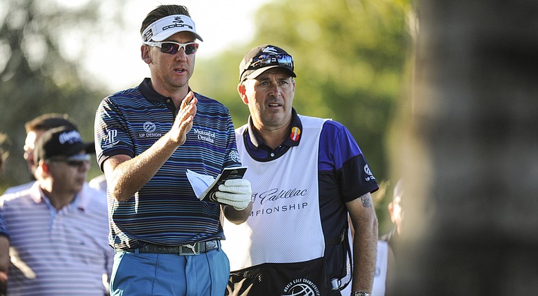 Ian Poulter speaks with his caddie before chipping a shot from the rough behind palm trees on the 18th hole during the second round of the WGC-Cadillac Championship.