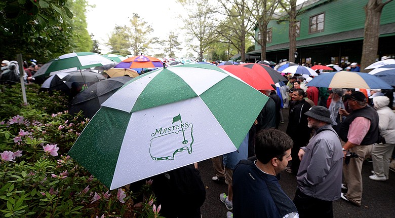 Patrons carrying umbrellas are evacuated from the course after play was suspended due to weather on Monday at Augusta national.