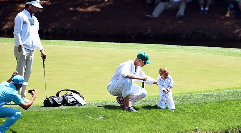 Rickie Fowler (bottom left) helps the Watson family chronicle the Par 3 Contest on Wednesday, with Caleb, 2, hitting his own shot down into the water.