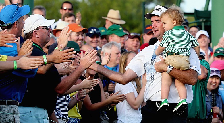 Bubba Watson holds his 2-year-old son, Caleb, while they celebrate with fans lining the 18th green after his three-shot victory at the Masters.