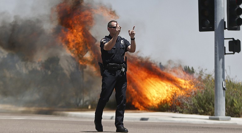 A Carlsbad, Calif., police officer turns traffic away from a wildfire Thursday.