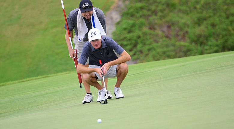 Nicholas Lindheim (front) lines up a 10-foot par putt on No. 9 with his caddie Carter "Hurricane" Hennessey during the second round of the 2014 U.S. Open Sectional Qualifying at Quail Valley in Vero Beach, Fla. Lindheim would make the putt to card a 1-under 71.