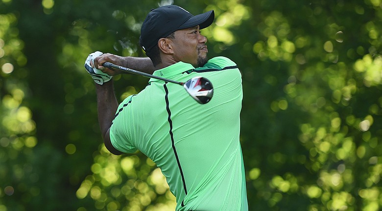 Tiger Woods watches his tee shot on the 14th hole during a first round of the Quicken Loans National.
