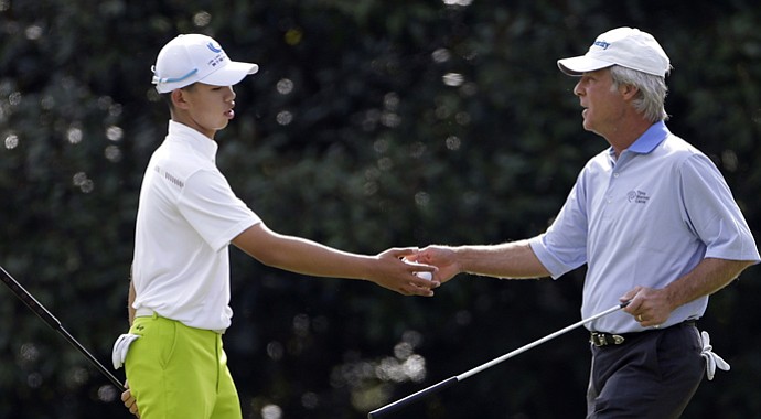 Ben Crenshaw, right, hands a golf ball to amateur Tianlang Guan, of China, on the 11th hole during a practice round for the Masters.