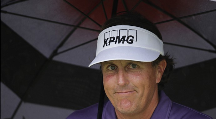 Phil Mickelson takes shelter under an umbrella on No. 2 at Augusta National during the second round of the 2013 Masters, with weather becoming a factor early Friday.