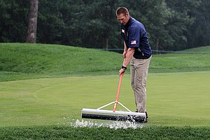 Grounds crew squeegees the 6th green after a near hour delay during the finals of the U.S. Amateur at Olympia Fields (Ill.) Country Club. 